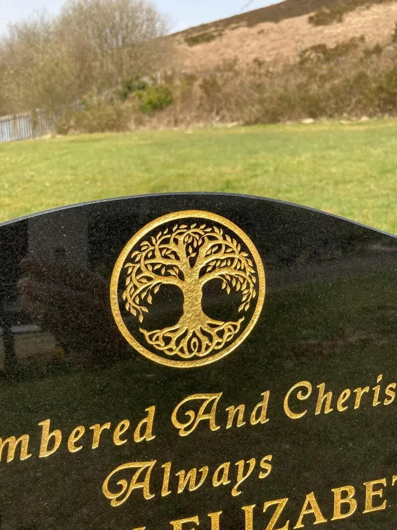 Close-up of a hand-gilded tree of life roundel and gold leaf lettering cut into polished granite by FR Terrazzo, Rhondda Cynon Taff